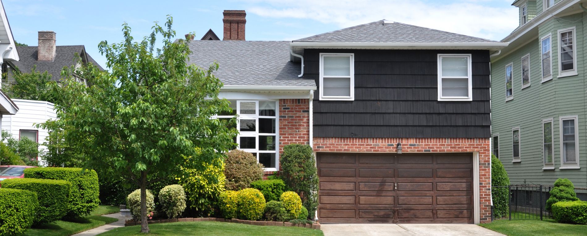 Home landscaped front yard lawn with a wooden garage door